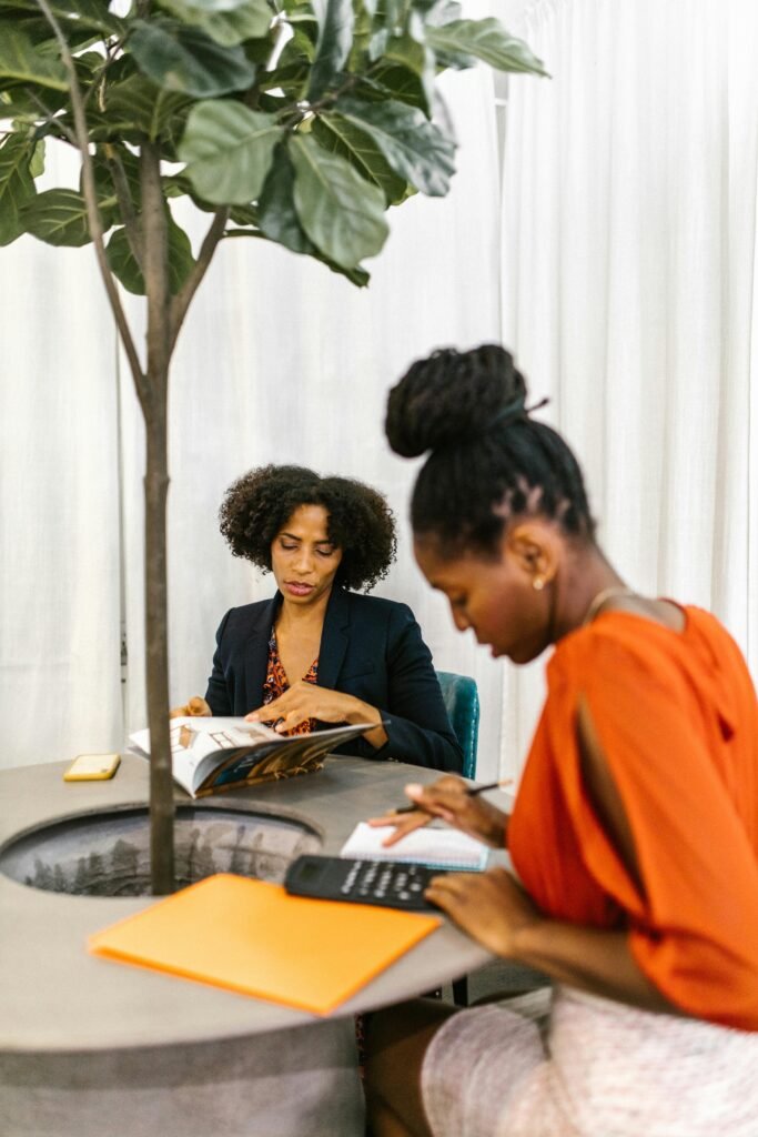 Two African American women collaborate in a contemporary office setting.